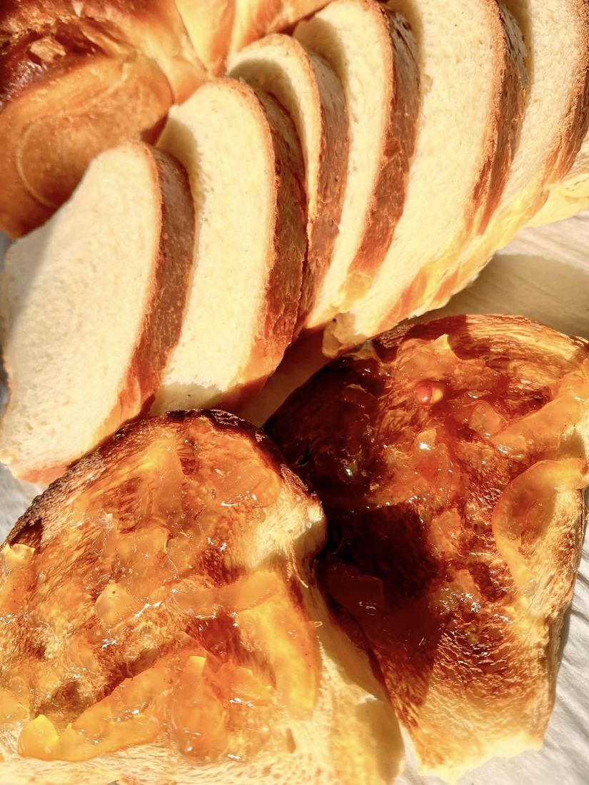 Thick slices of soft bread beside cheese-topped rolls on a metal tray.